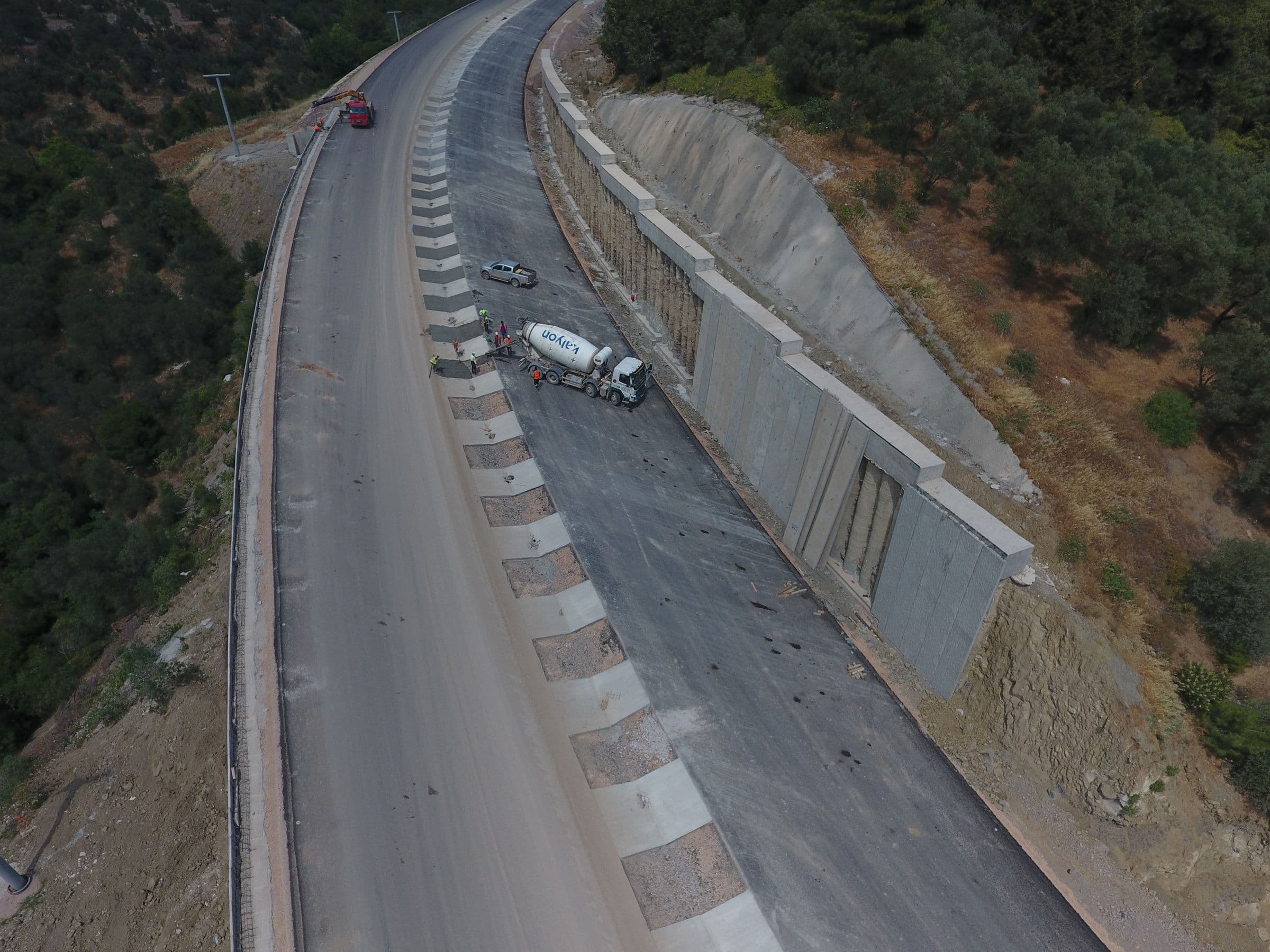 Vue aérienne d’une route de montagne en construction le long d’un mur de soutènement en béton.